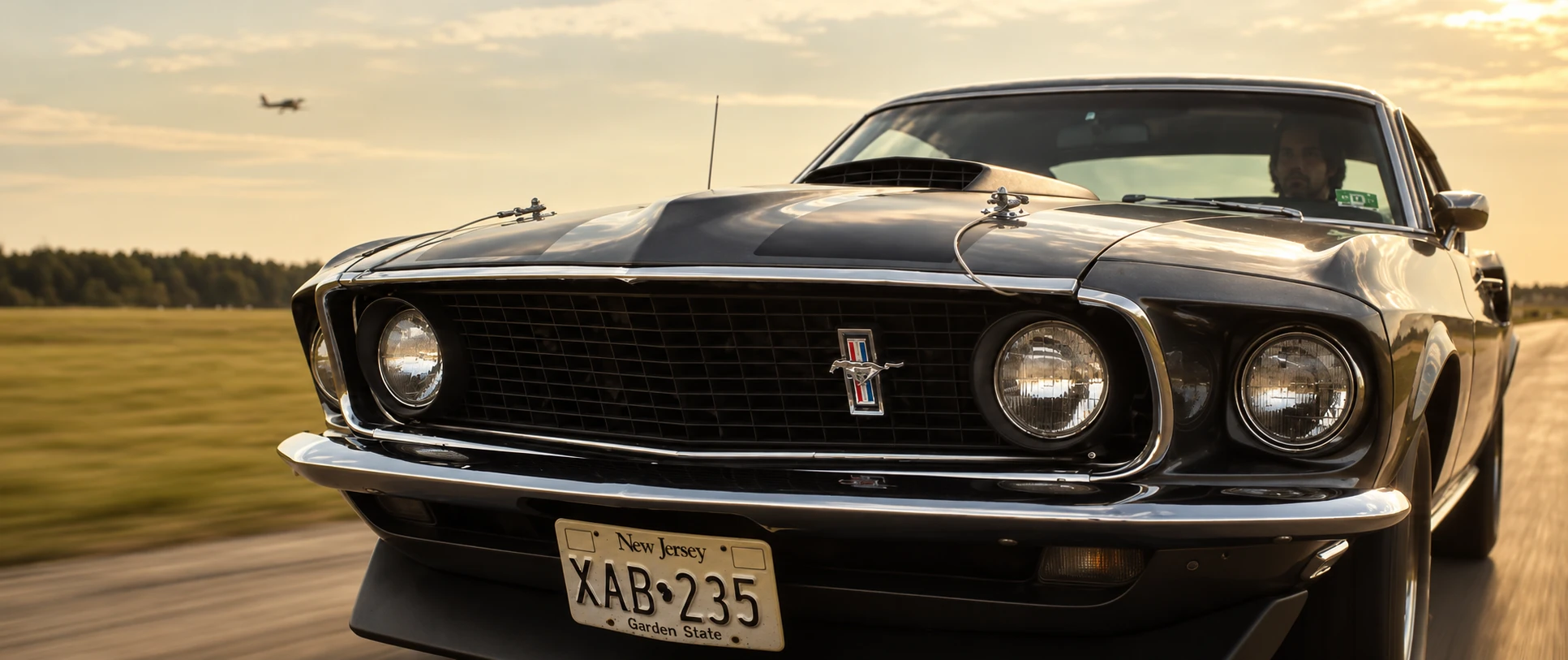 Low front tracking view of the dark grey 1969 Mustang Mach 1 associated with John Wick.